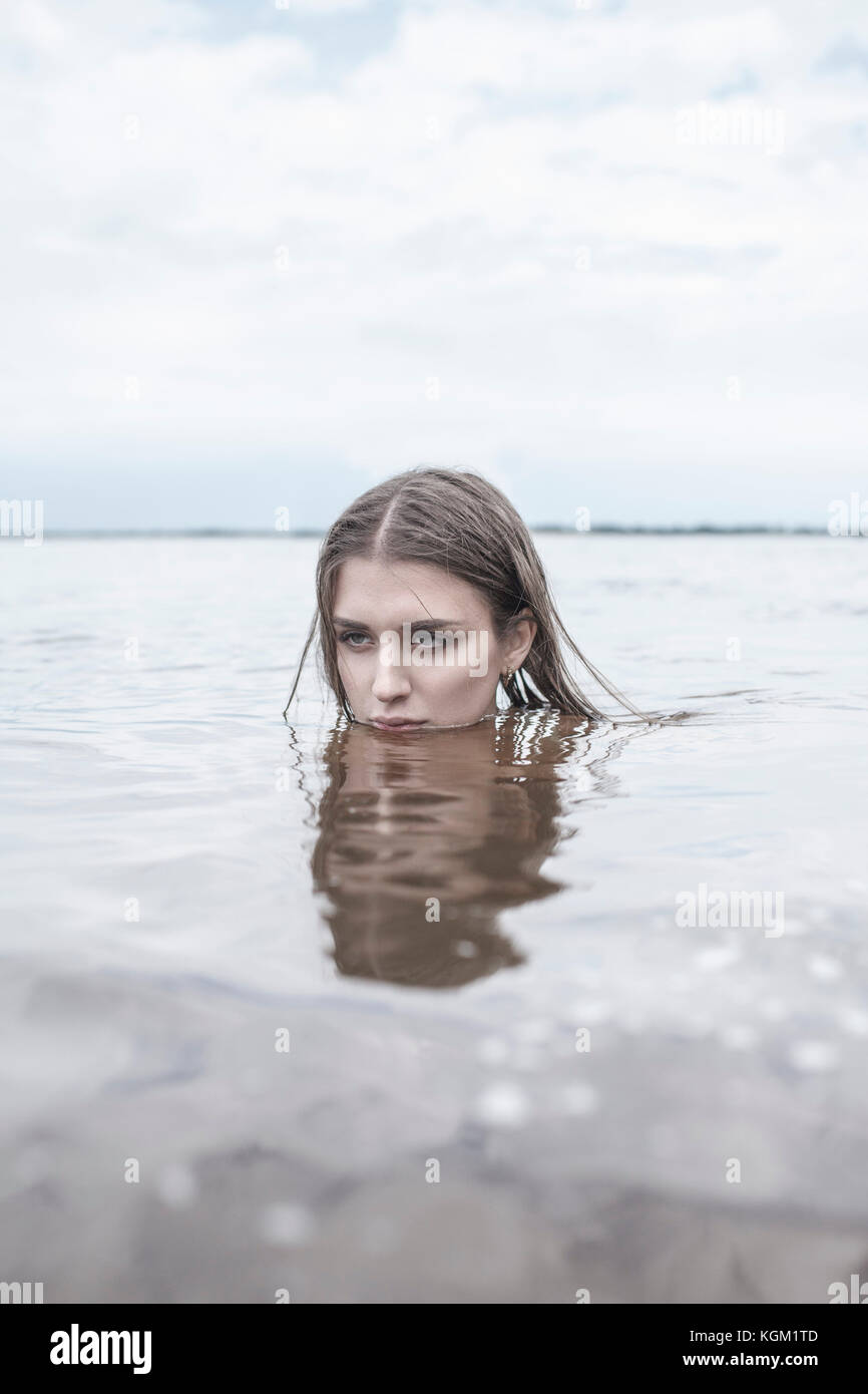 Young woman swimming in lake against sky Banque D'Images