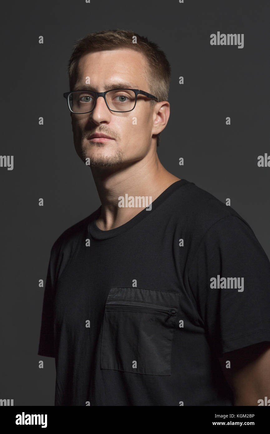 Portrait of mid adult man wearing eyeglasses debout contre l'arrière-plan gris Banque D'Images