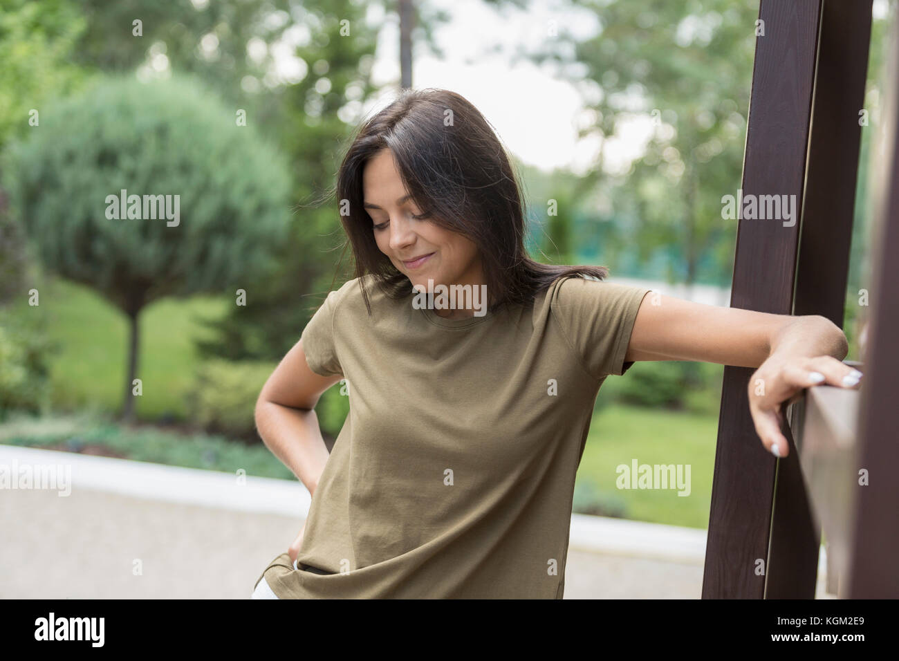 Smiling woman looking down while standing by railing Banque D'Images
