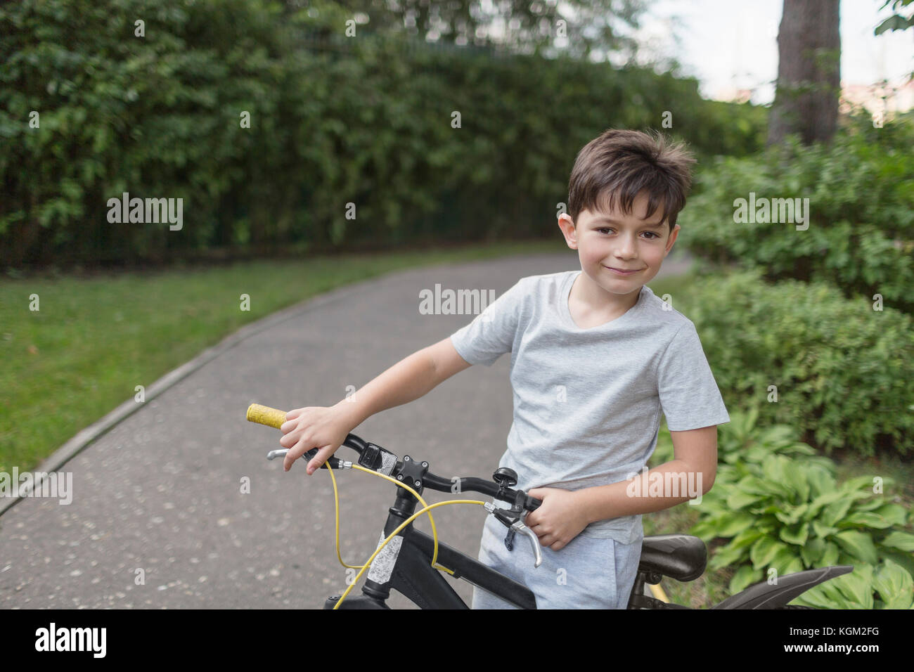 Portrait of boy riding bicycle on street contre des plantes Banque D'Images