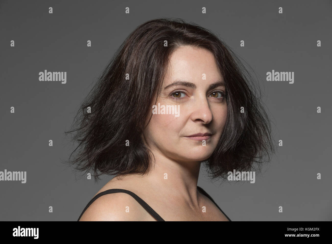 Close-up portrait of mature femme aux cheveux courts à l'arrière-plan gris Banque D'Images