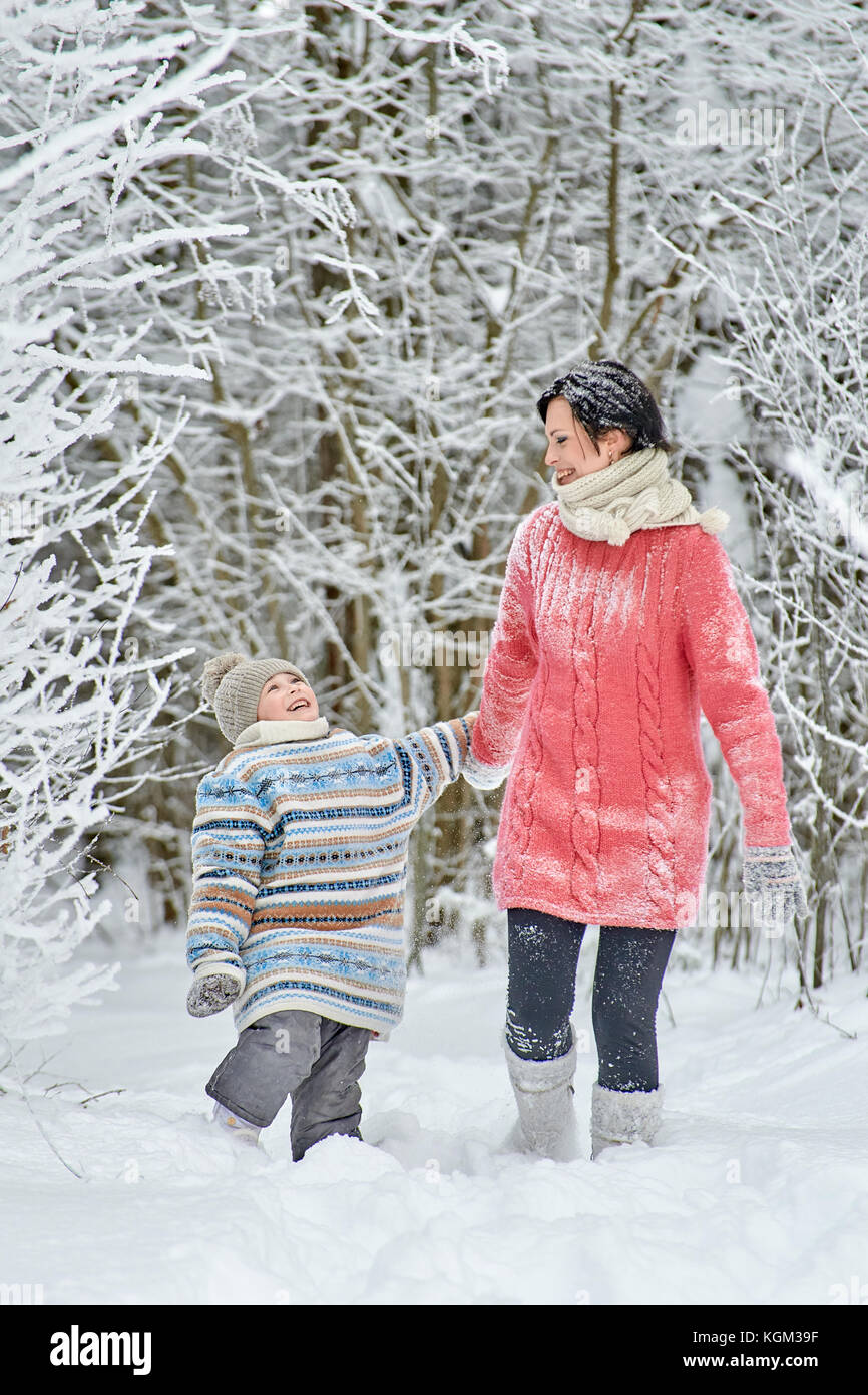 Maman avec une petite fille passer une journée dans la forêt d'hiver. Ils passent par des congères, ils reniflent la neige des branches d'arbres gelés et ri Banque D'Images
