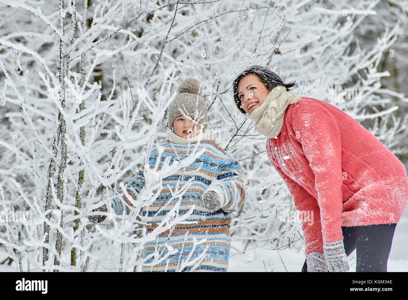 Maman avec une petite fille passer une journée dans la forêt d'hiver. Ils passent par des congères, ils reniflent la neige des branches d'arbres gelés et ri Banque D'Images