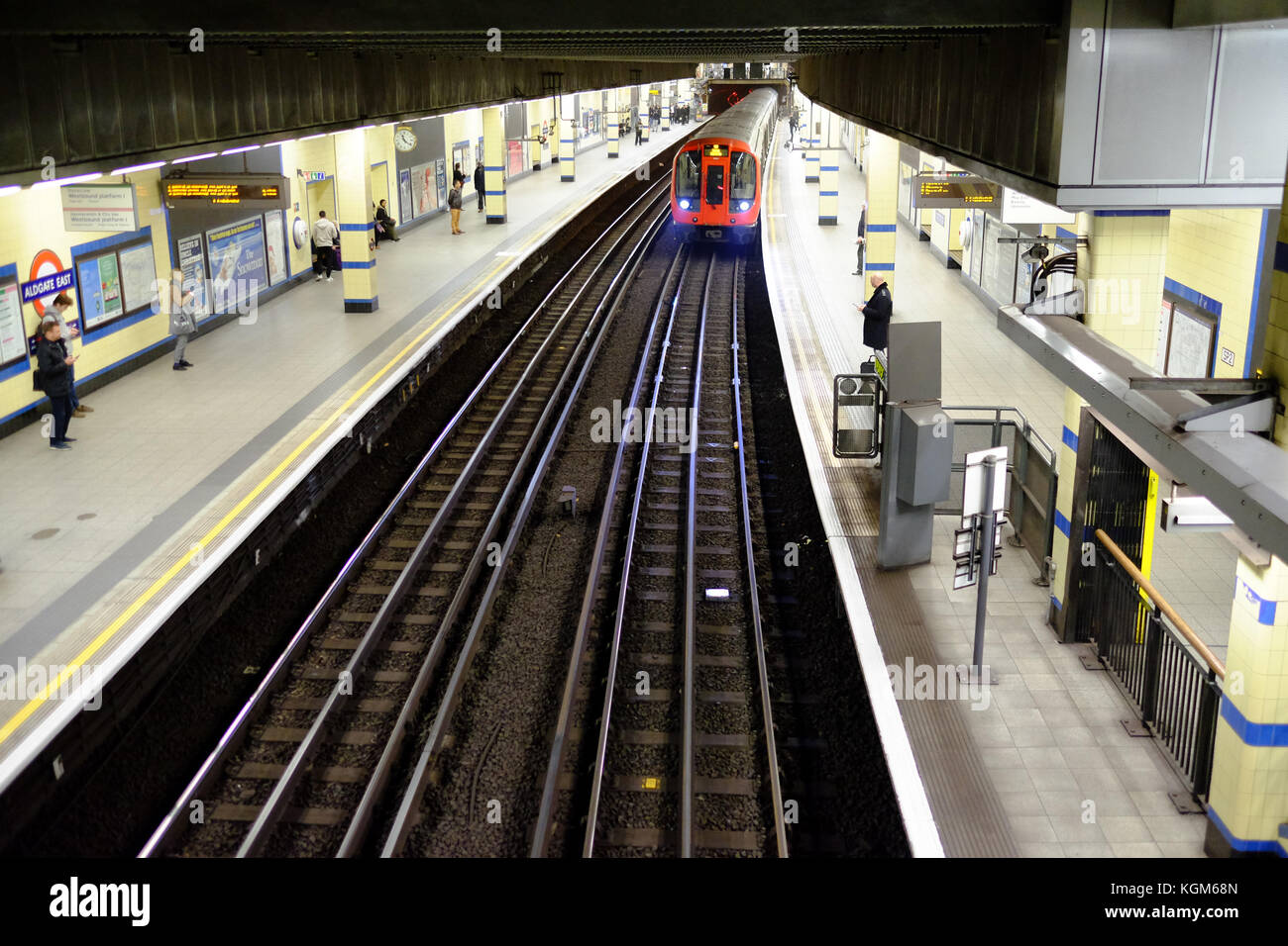 Une rame de métro à la plate-forme de la station Aldgate East sur le système de métro de Londres avec les usagers en attente Banque D'Images