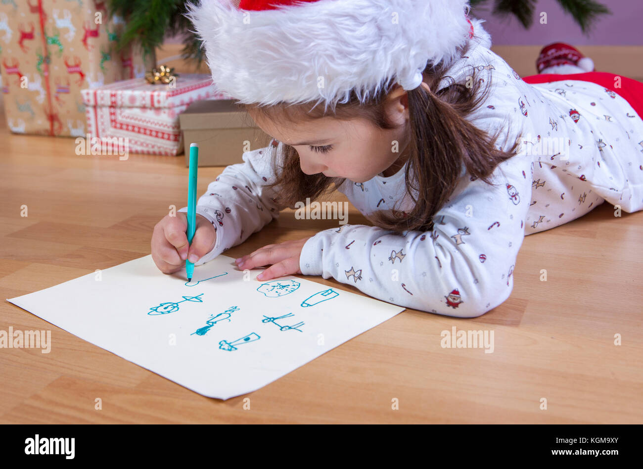 Petite fille de préparer la lettre de Santa. Elle peindre les cadeaux qu'elle veut. Concept de pré-reader Banque D'Images