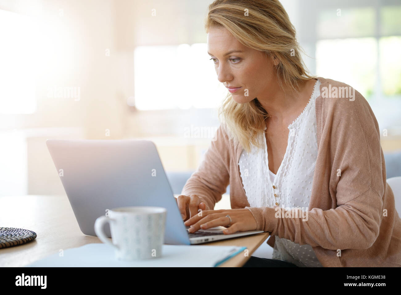 Attractive blonde woman working on laptop computer at home Banque D'Images