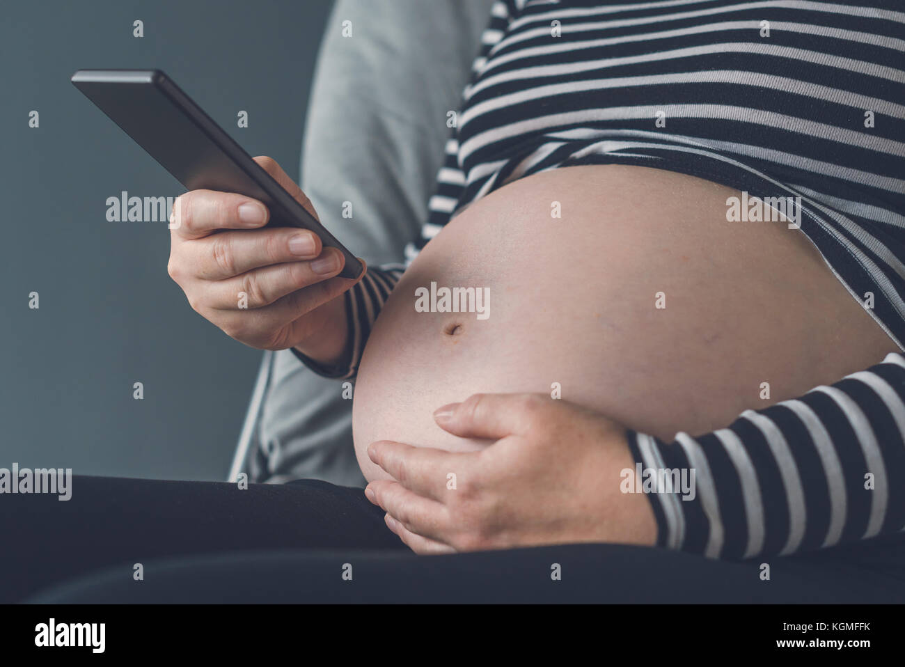Femme enceinte en utilisant son smartphone pendant la grossesse Banque D'Images