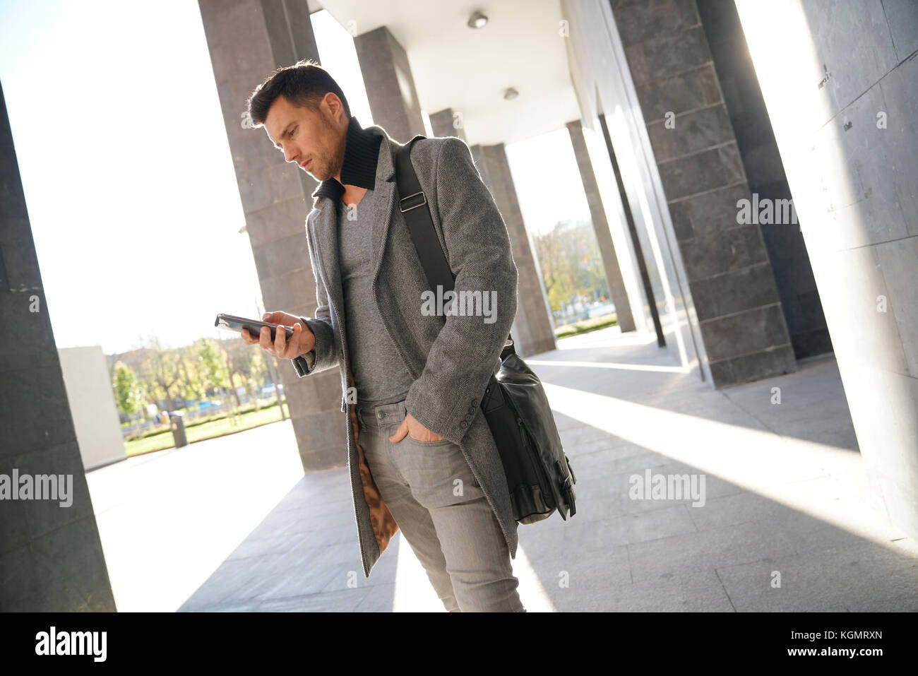 Trendy businessman walking by Modern building Banque D'Images