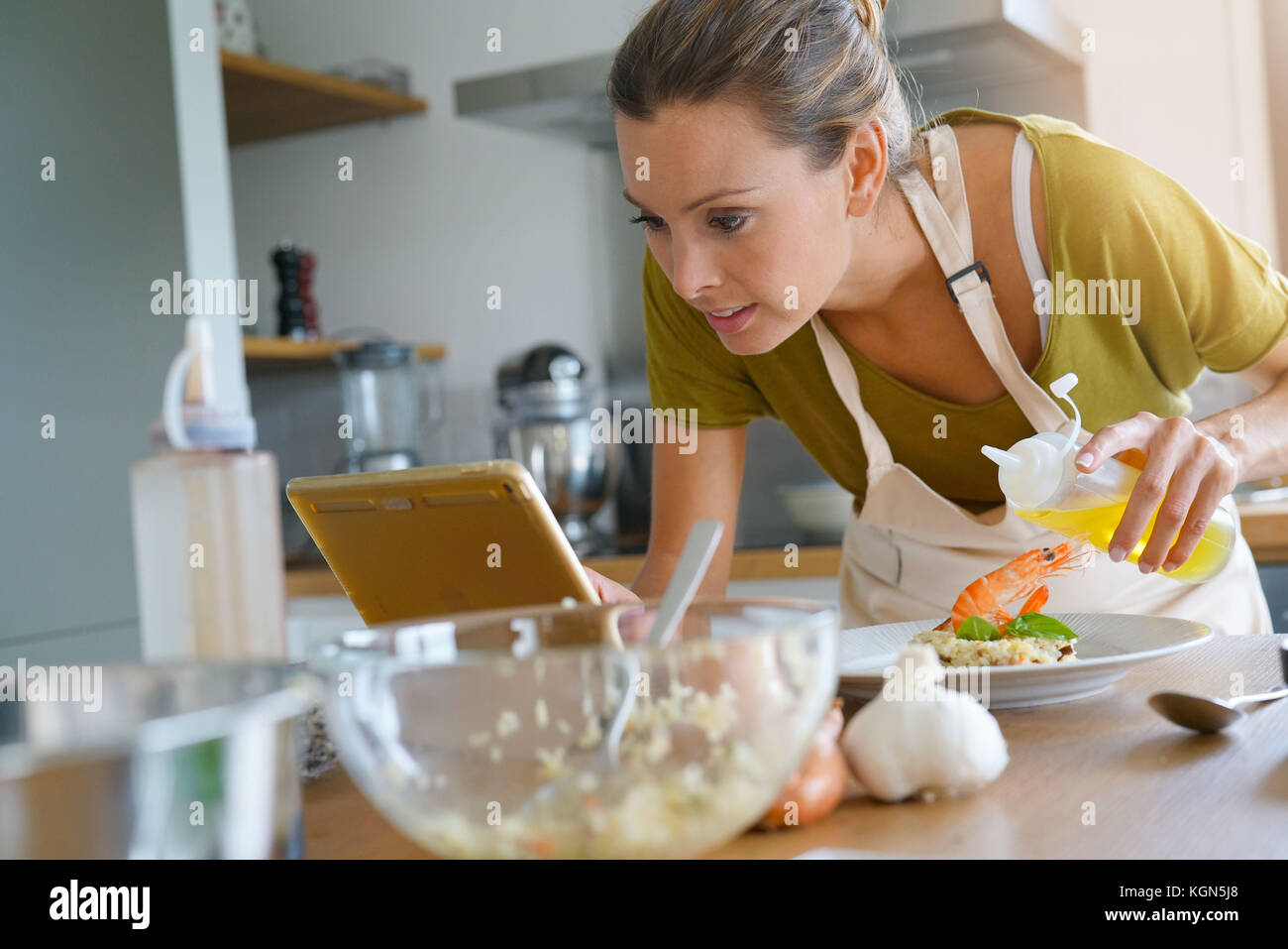 Femme dans la cuisine préparer un plat, recette lecture sur tablette numérique Banque D'Images