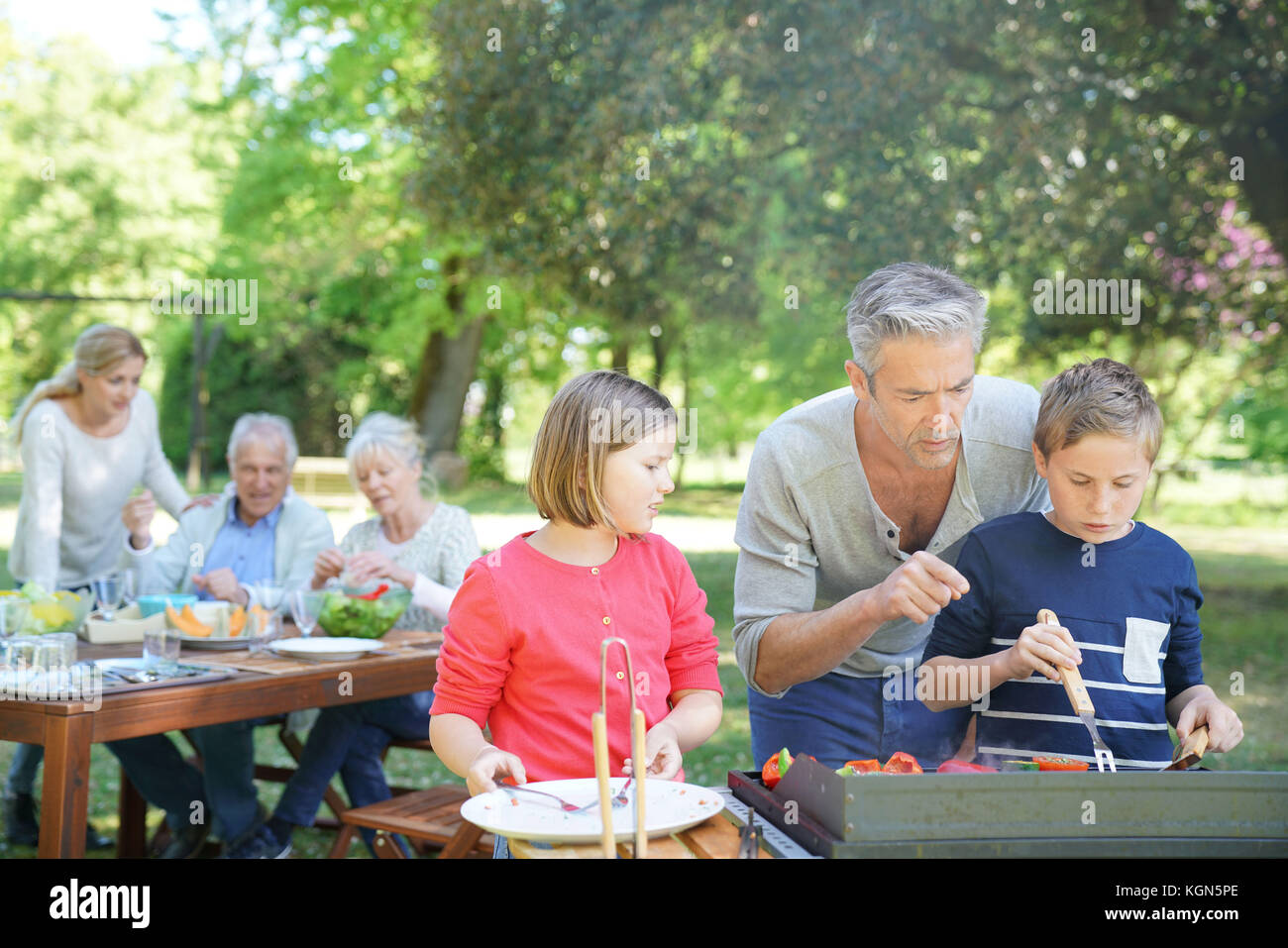 Homme avec enfants dans la cuisine barbecue pour la famille Banque D'Images