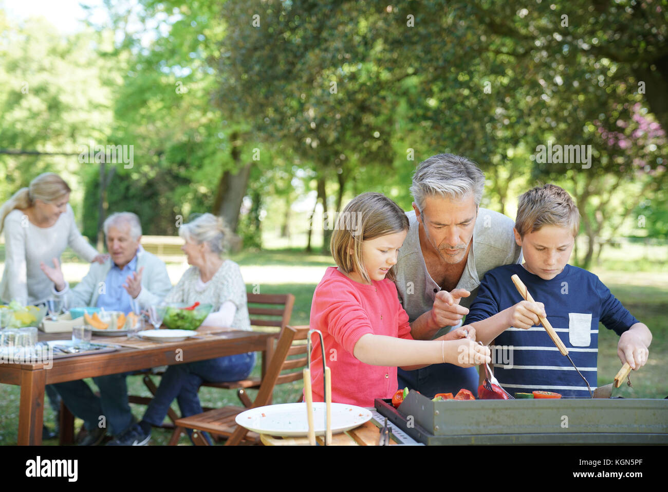 Homme avec enfants dans la cuisine barbecue pour la famille Banque D'Images