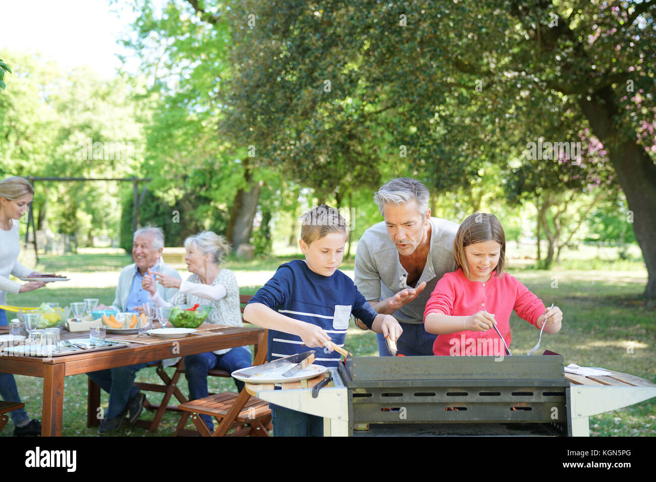 Homme avec enfants dans la cuisine barbecue pour la famille Banque D'Images
