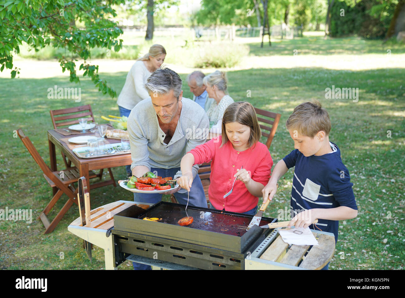 Homme avec enfants dans la cuisine barbecue pour la famille Banque D'Images
