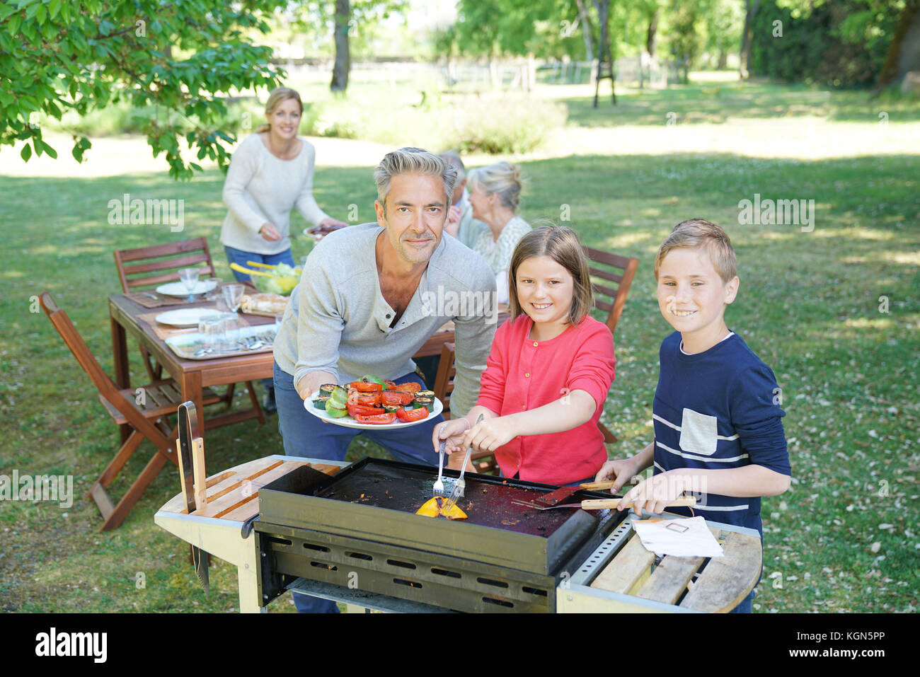 Homme avec enfants dans la cuisine barbecue pour la famille Banque D'Images