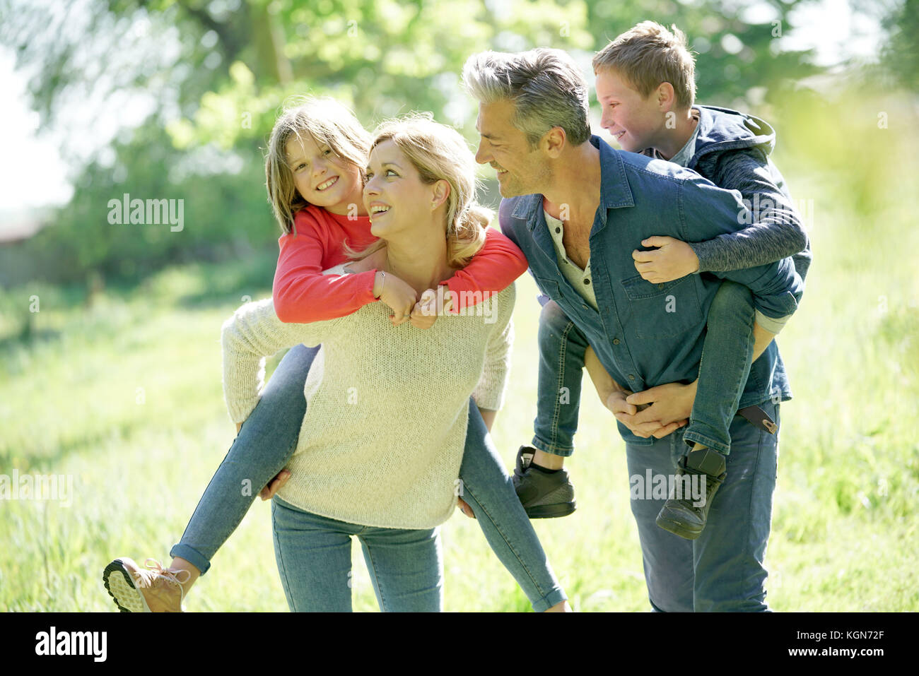 Les parents qui piggyback ride to kids in countryside Banque D'Images