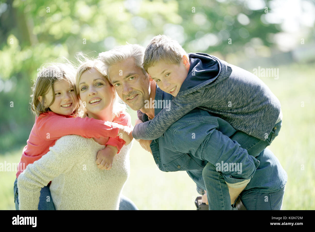 Les parents qui piggyback ride to kids in countryside Banque D'Images