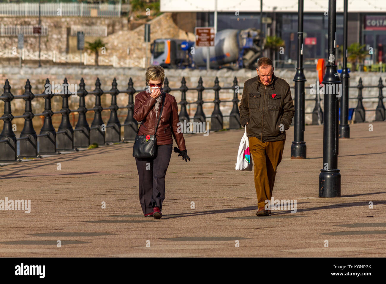 Un vieux couple en train de marcher le long de la promenade, un jour ensoleillé mais froid amène les gens à Torquay, novembre 2017. Banque D'Images