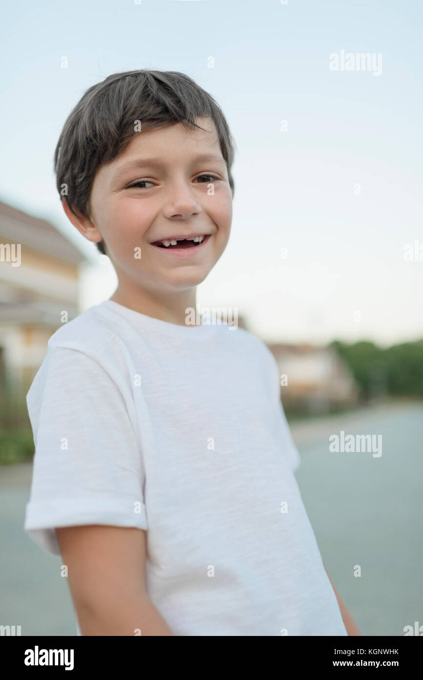 Portrait of smiling boy standing en ville contre un ciel clair Banque D'Images