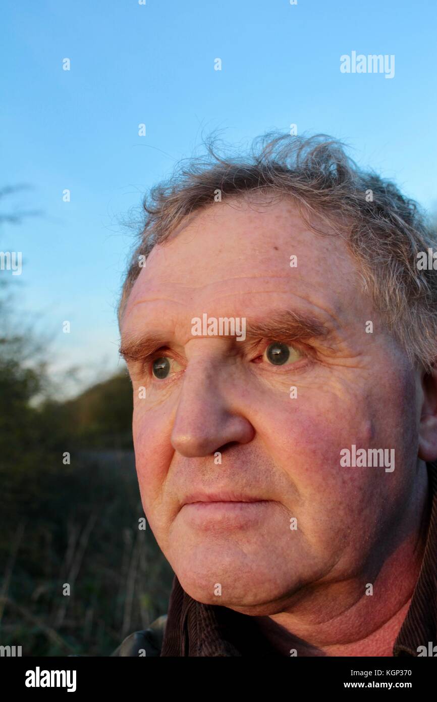 Close up visage de 60 ans à la recherche de l'homme blanc en soleil du soir au wildfowl sur un lac Banque D'Images