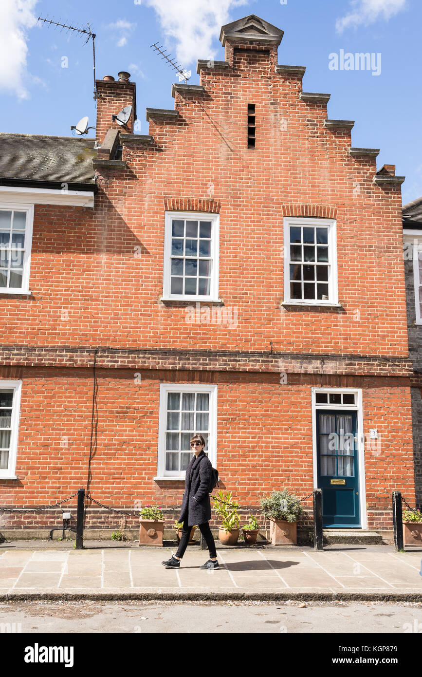 Hipster femme marche sur le trottoir en face d'une maison victorienne restaurée edwardian House à London, UK Banque D'Images
