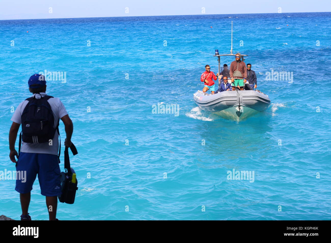 Un homme monte à bord d'un petit bateau gonflable Vigilanza sur l'eau de mer bleue dans un parc national sarde. Banque D'Images