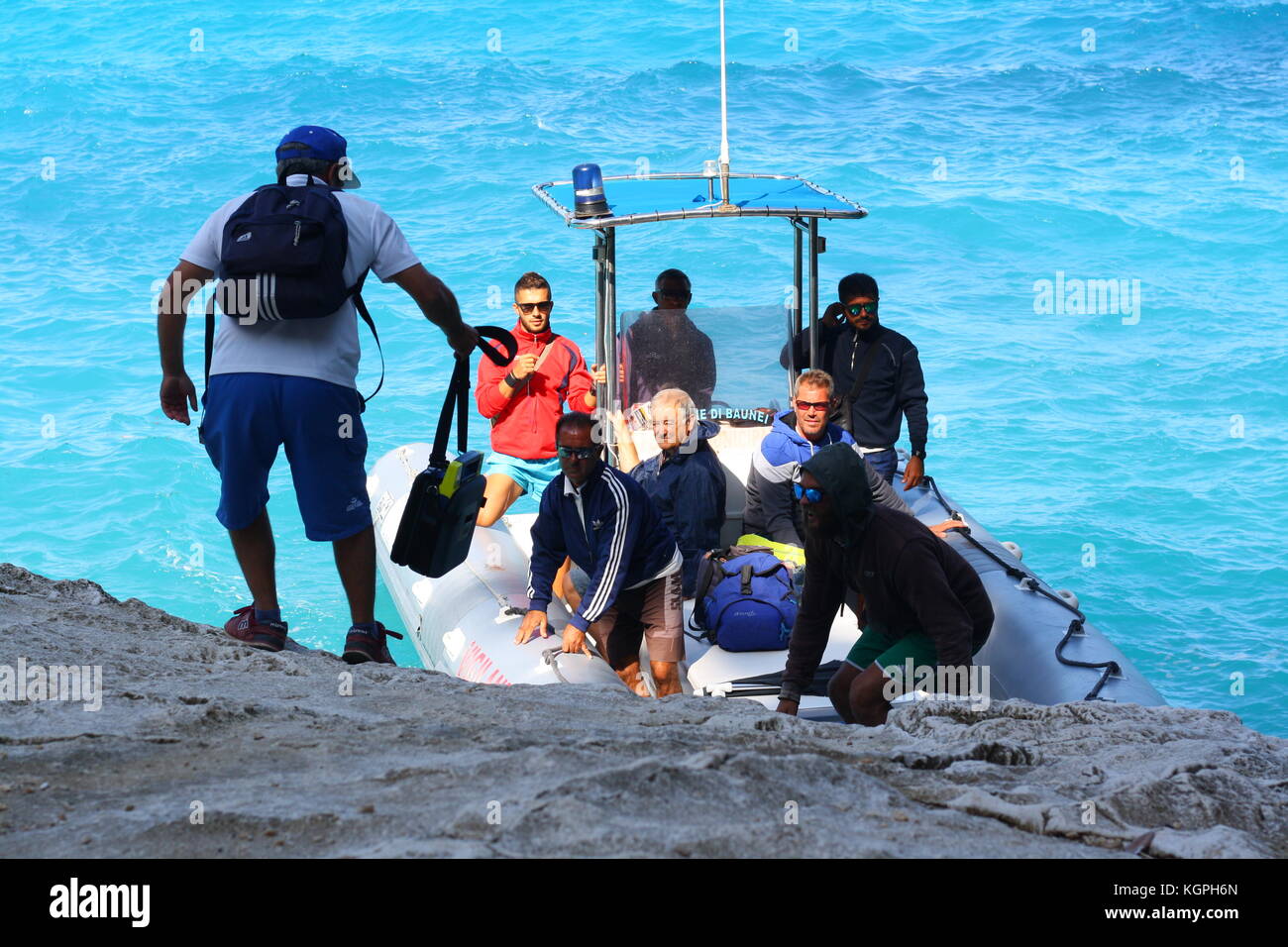 Un homme monte à bord d'un petit bateau gonflable Vigilanza sur l'eau de mer bleue dans un parc national sarde. Banque D'Images