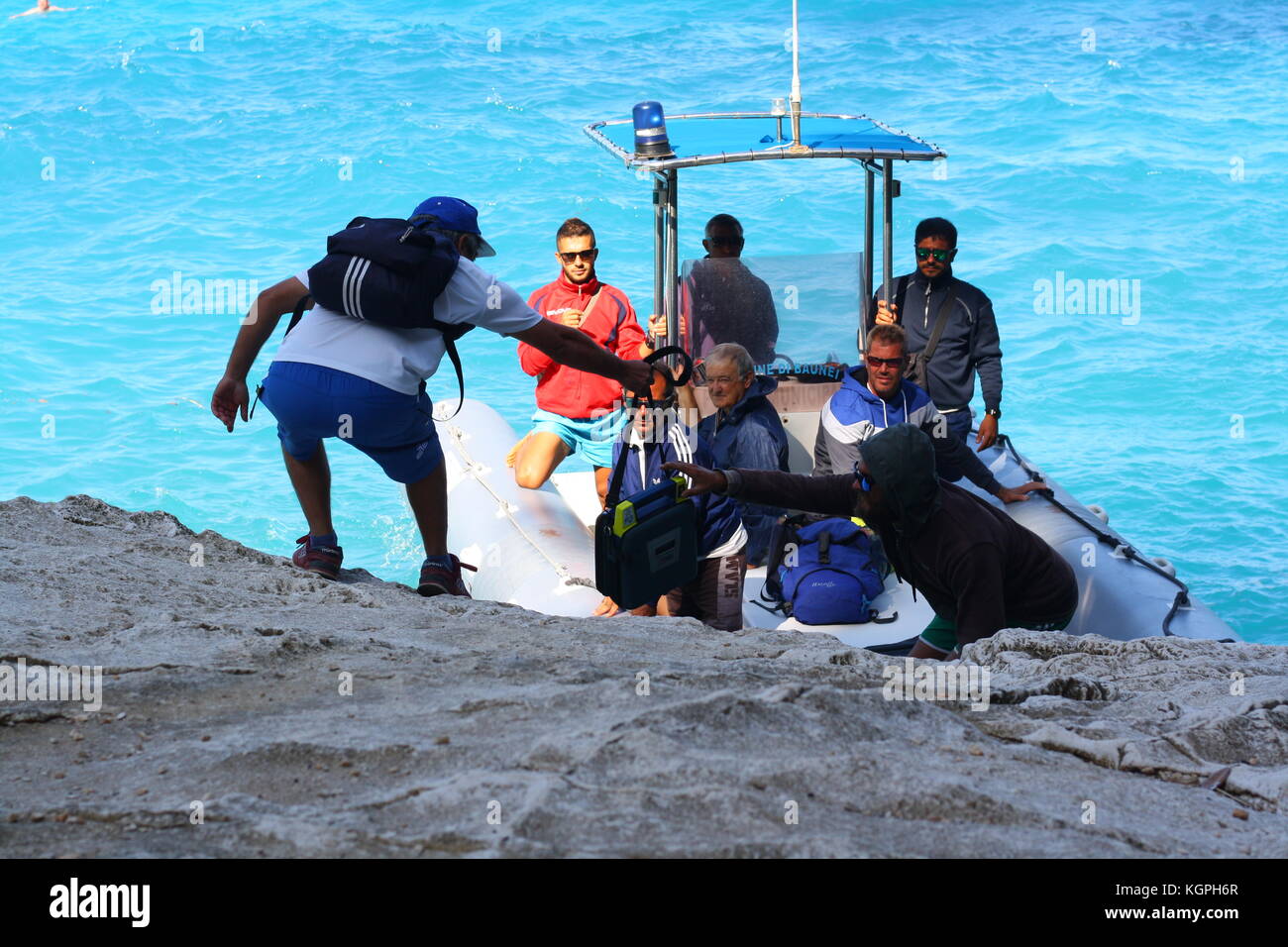 Un homme monte à bord d'un petit bateau gonflable Vigilanza sur l'eau de mer bleue dans un parc national sarde. Banque D'Images