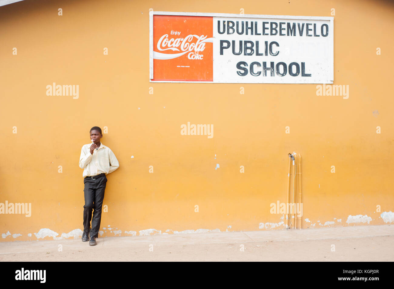 Garçon d'Afrique noire à l'extérieur de détente avec un parrainage de coke. L'école élémentaire près de Cape Town, Afrique du Sud Banque D'Images