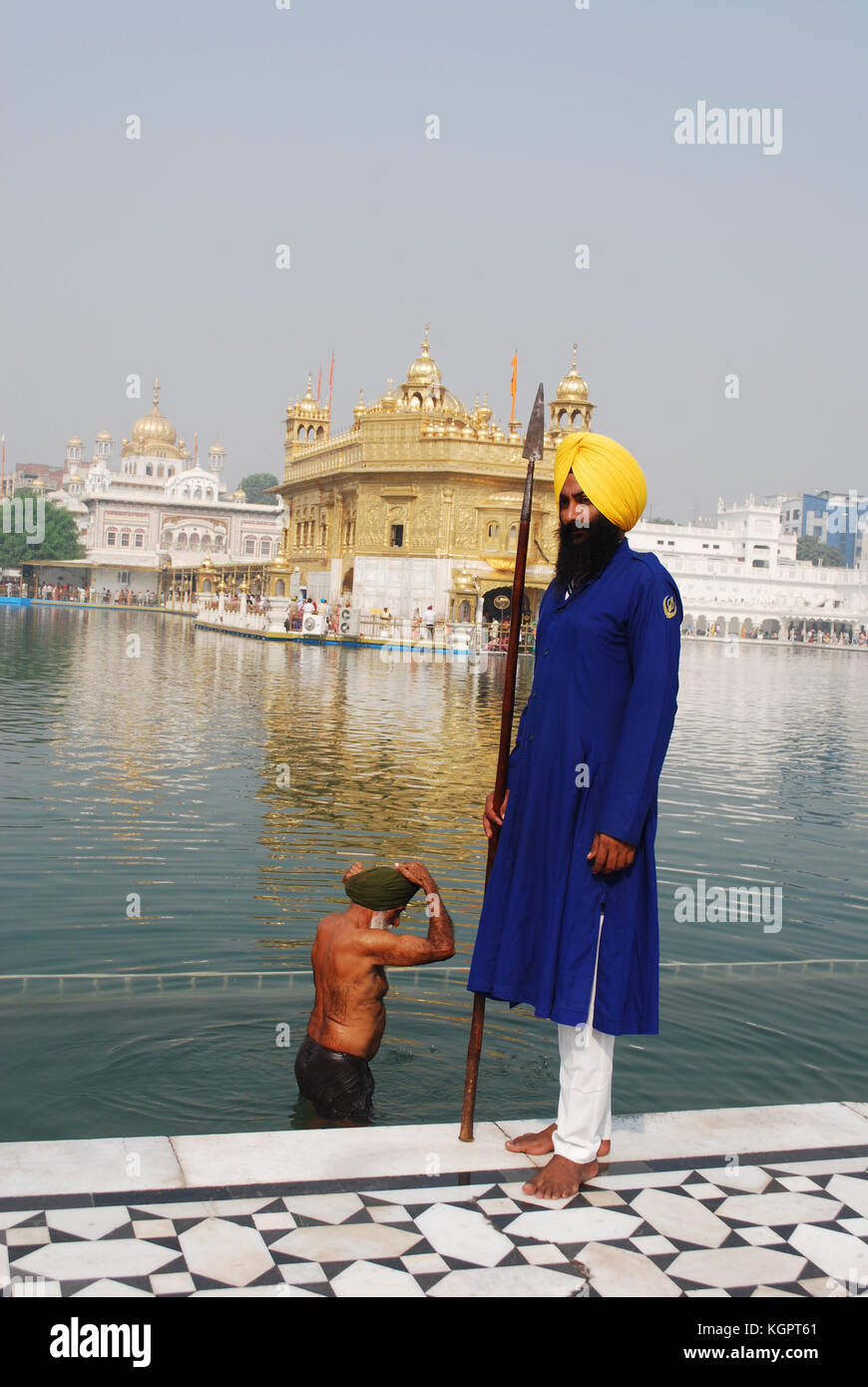 Un garde Sikh avec un homme derrière le sacré dans le bain l'Amrit Sarovar Lake, en face du Golden Temple, Amritsar, Punjab, India Banque D'Images