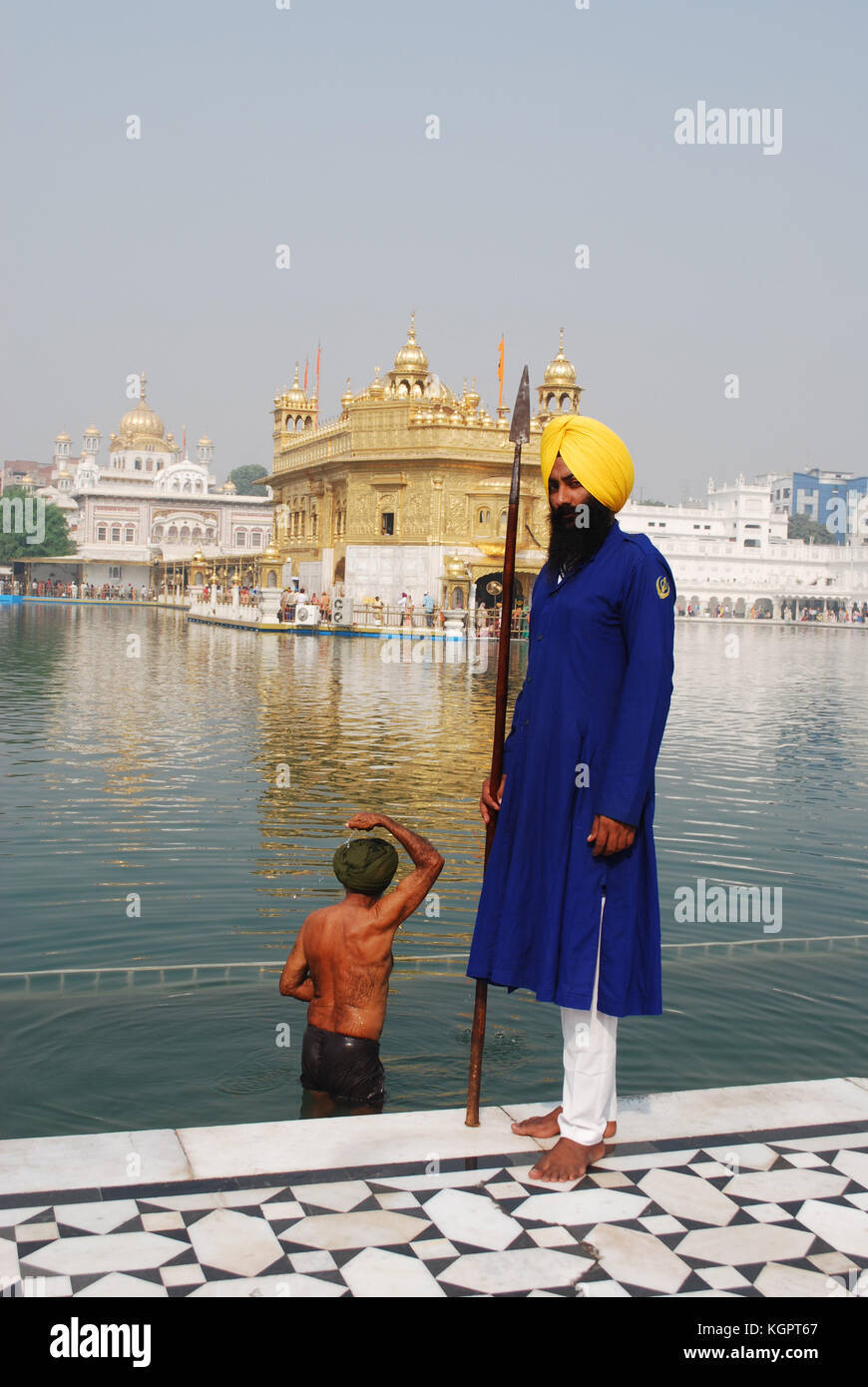 Un garde Sikh avec un homme derrière le sacré dans le bain l'Amrit Sarovar Lake, en face du Golden Temple, Amritsar, Punjab, India Banque D'Images