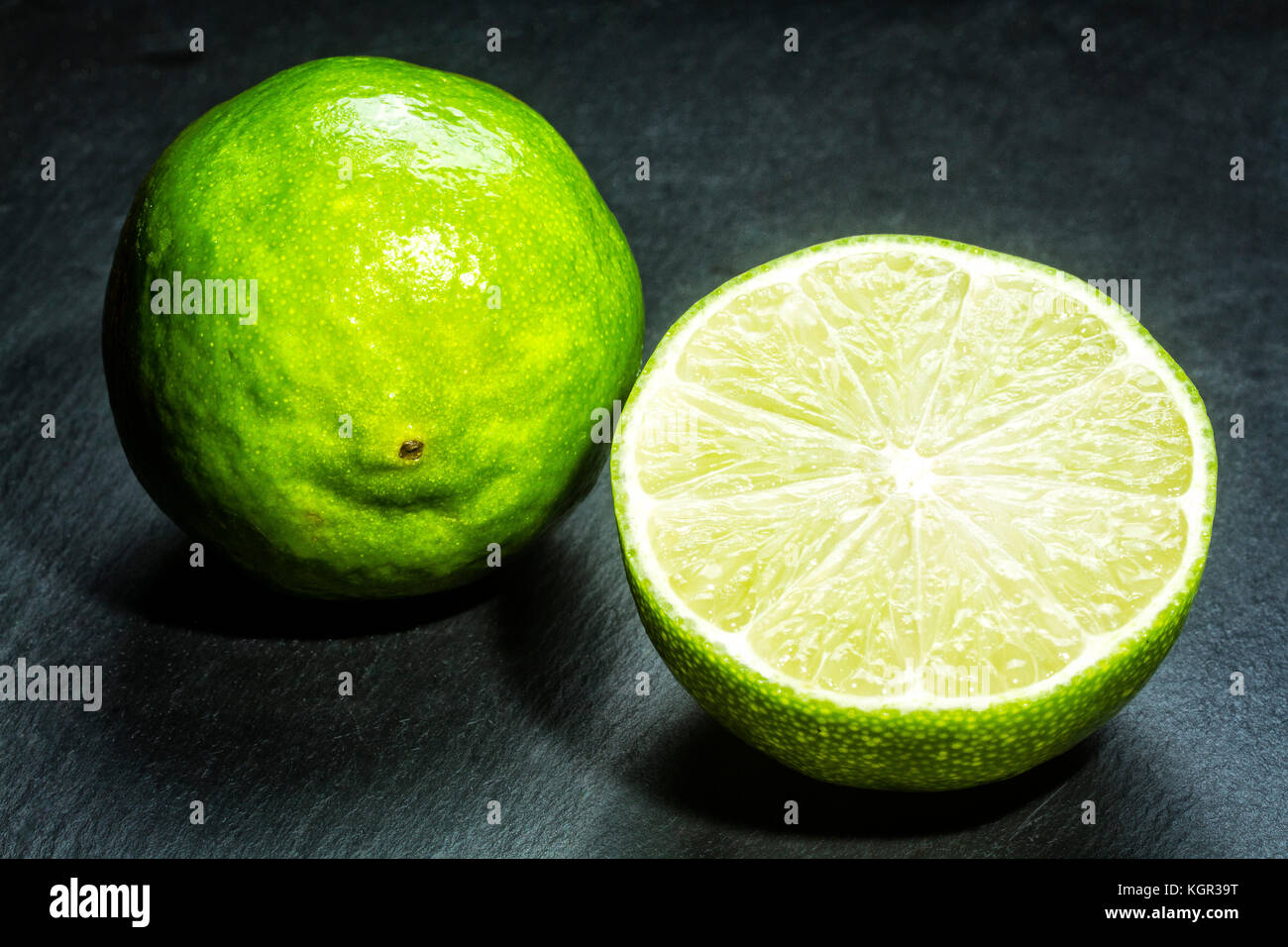 Lime (Citrus aurantifolia) sur une plaque en ardoise noire. Banque D'Images