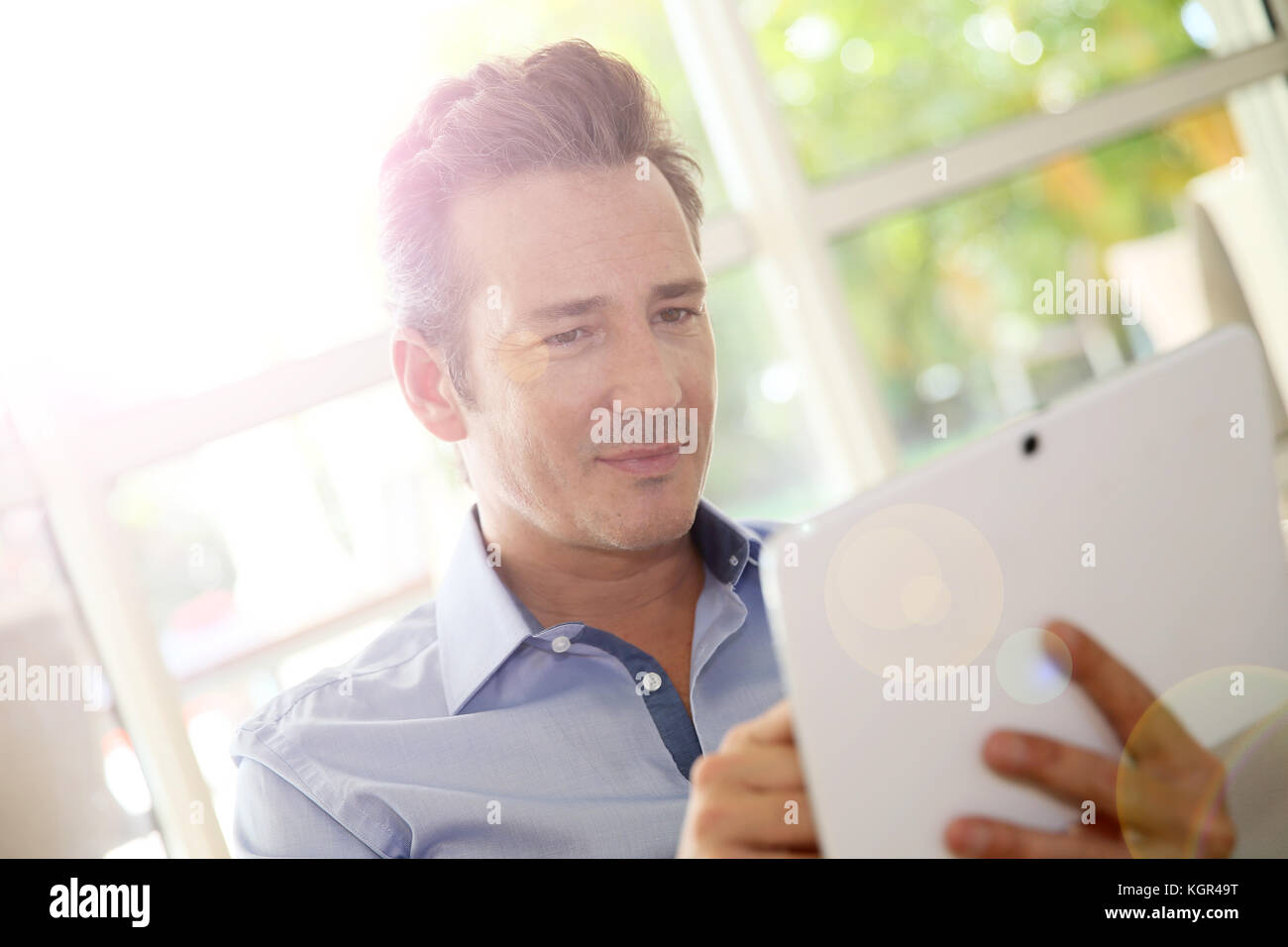Portrait d'homme d'âge moyen à la maison à l'aide de tablet Banque D'Images