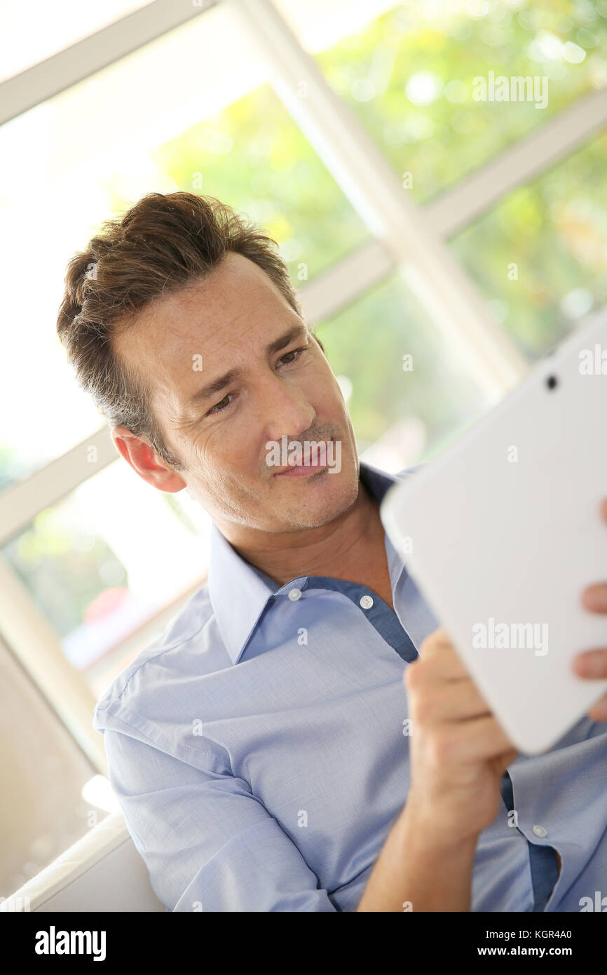 Portrait d'homme d'âge moyen à la maison à l'aide de tablet Banque D'Images