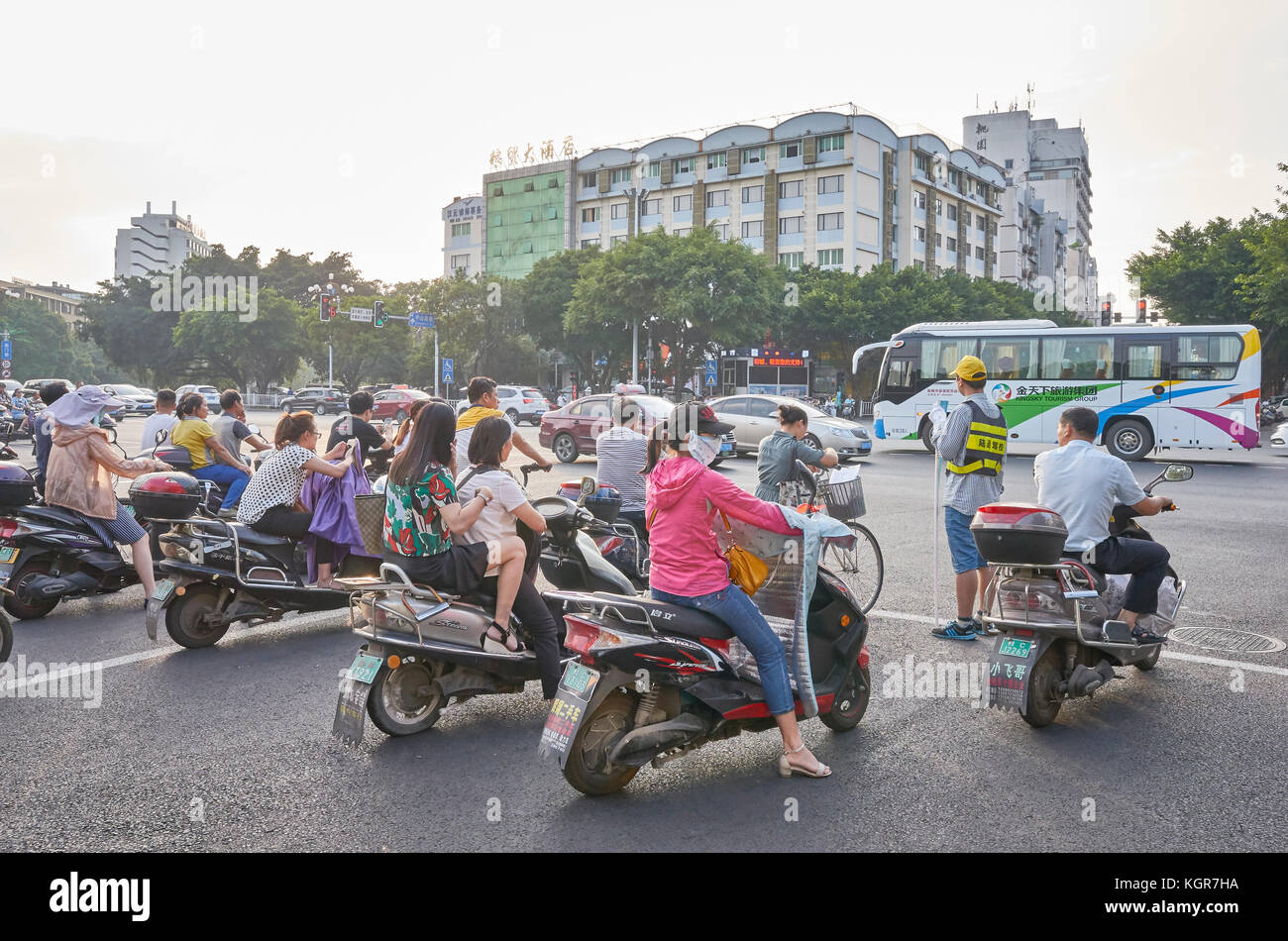 Guilin, Chine - 14 septembre 2017 : Scooters chauffeurs attendent pour feu vert sur une intersection au centre-ville de Guilin au lever du soleil. Banque D'Images