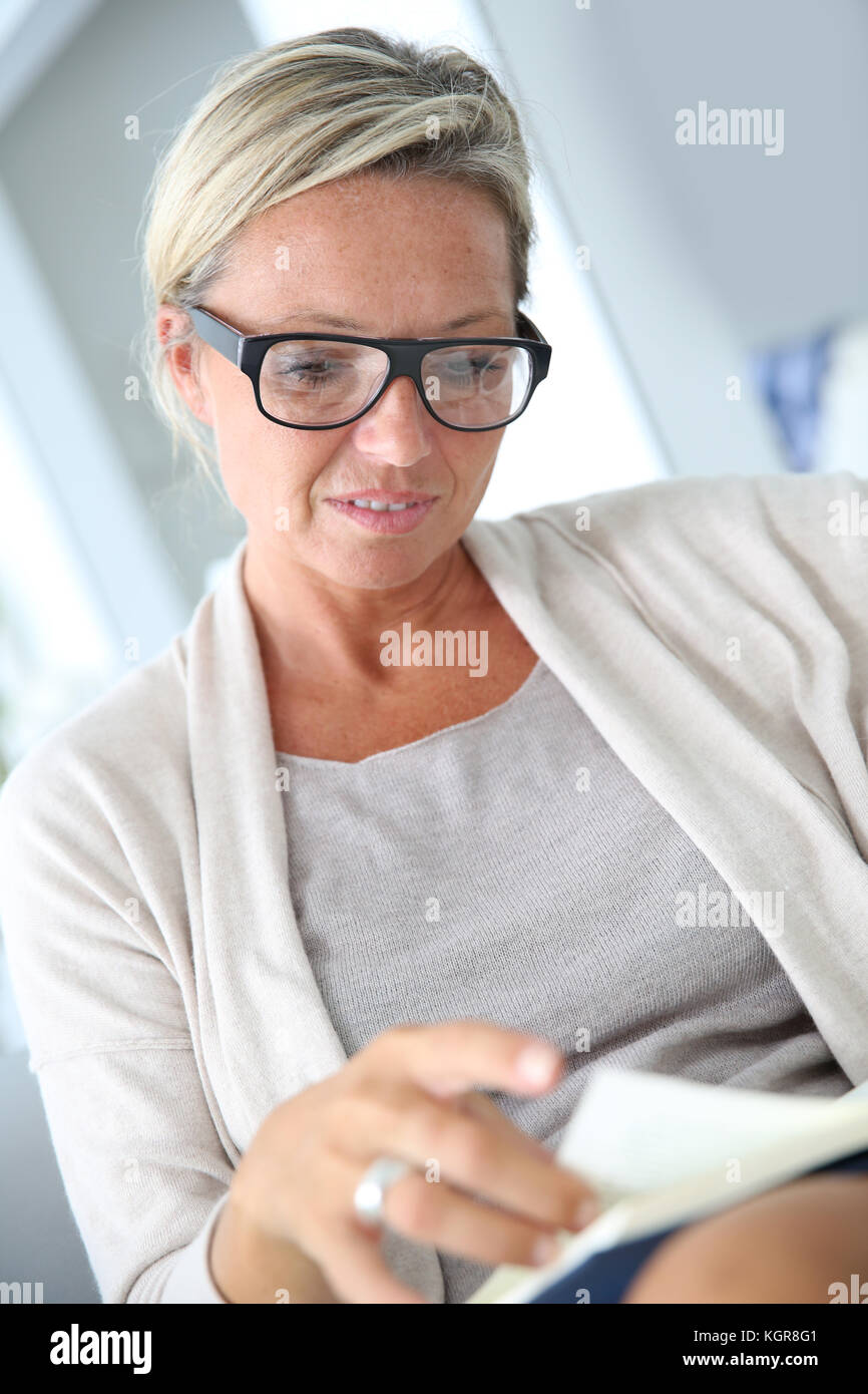 Blonde mature woman reading book Banque D'Images
