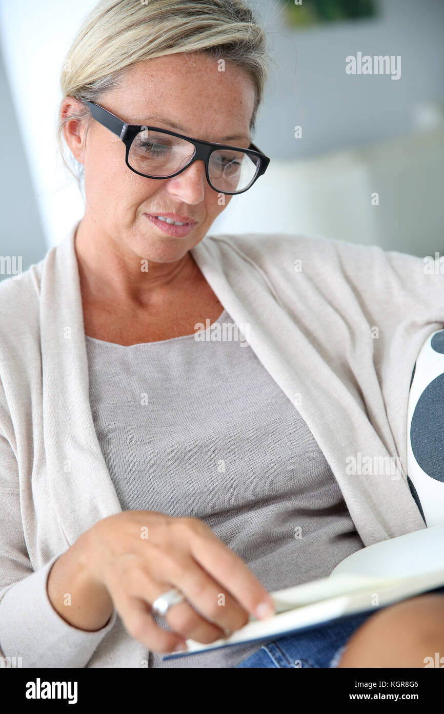 Blonde mature woman reading book Banque D'Images