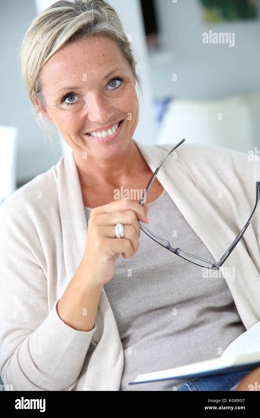 Blonde mature woman reading book Banque D'Images