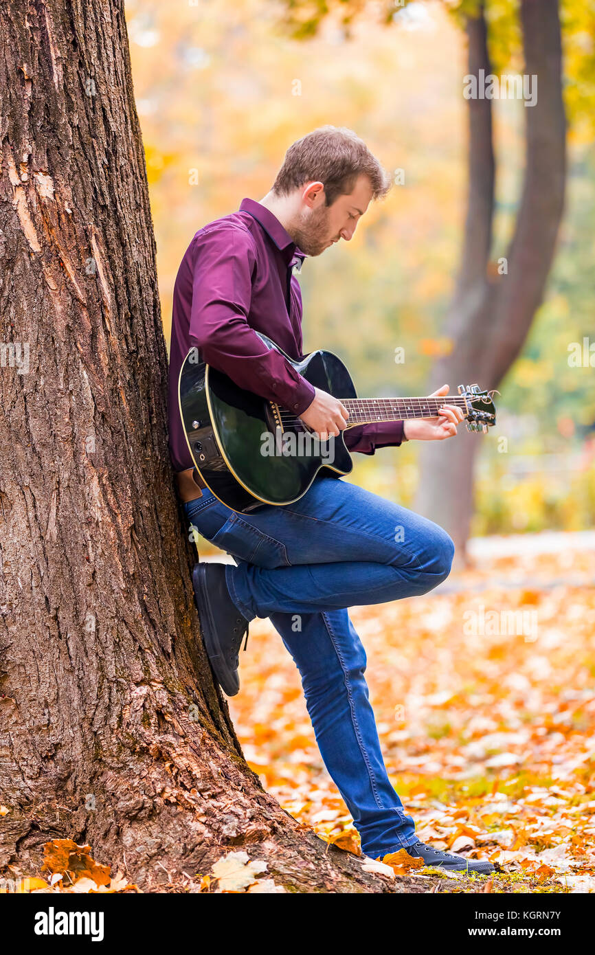 Jeune homme jouant de la guitare acoustique dans city park. Se concentrer sur la main. Banque D'Images