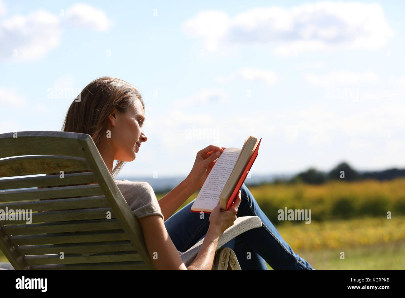 Woman Reading book in chaise longue Banque D'Images