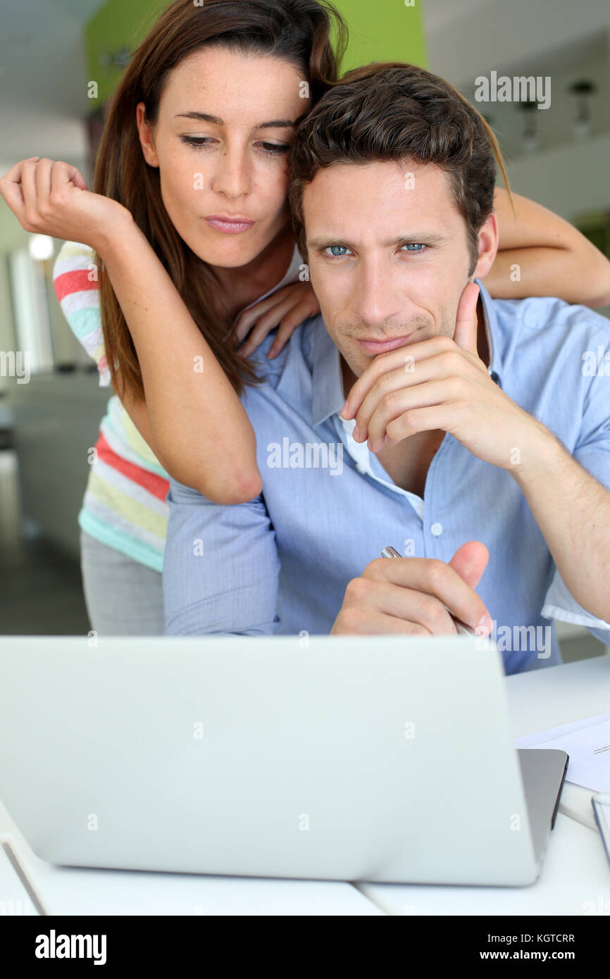 Couple looking at laptop avec expression perplexe Banque D'Images