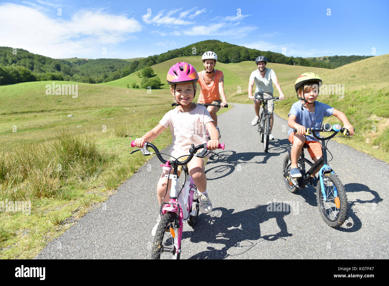 Vélos d'équitation de famille heureux dans la route de montagne Banque D'Images