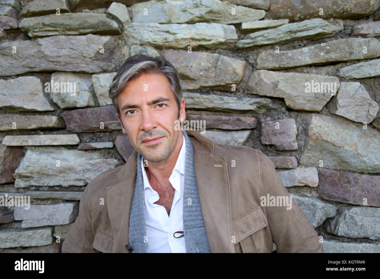 Man leaning on mur de pierre en campagne Banque D'Images