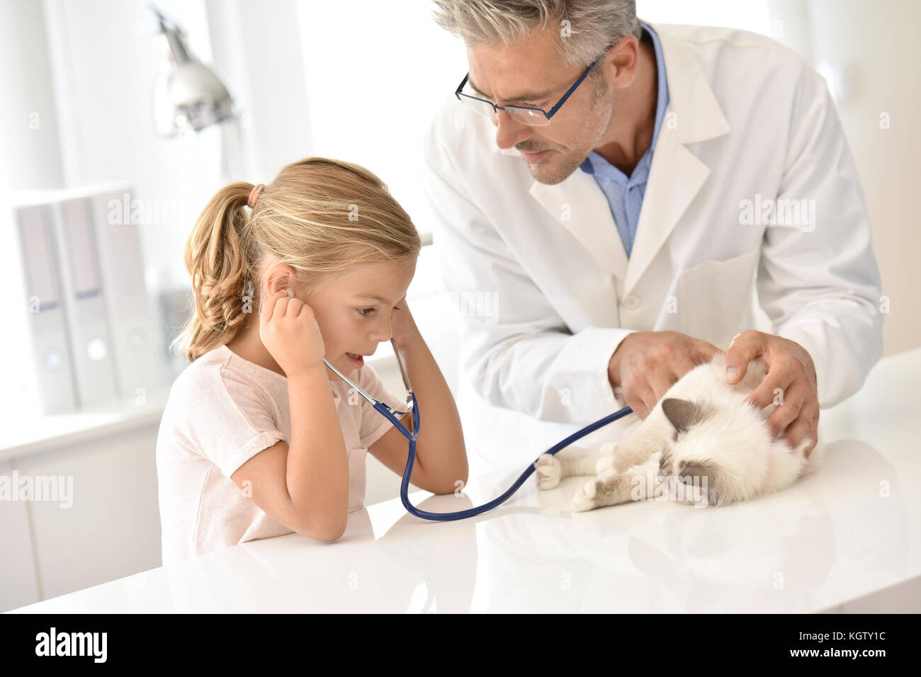 Petite fille chez le vétérinaire avec son chat, à l'écoute de son cœur Banque D'Images