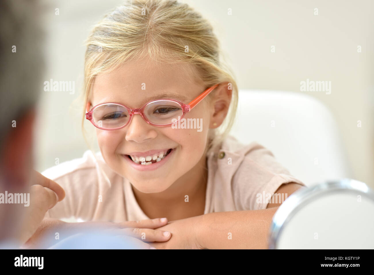 Petite fille à l'opticien pour essayer plusieurs lunettes Banque D'Images