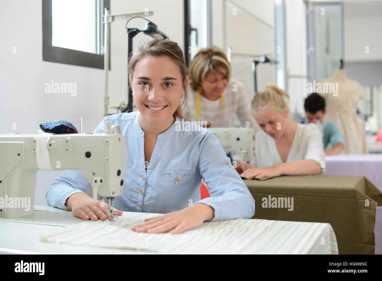 Jeune fille étudiante en classe de formation travaillant sur machine à coudre Banque D'Images