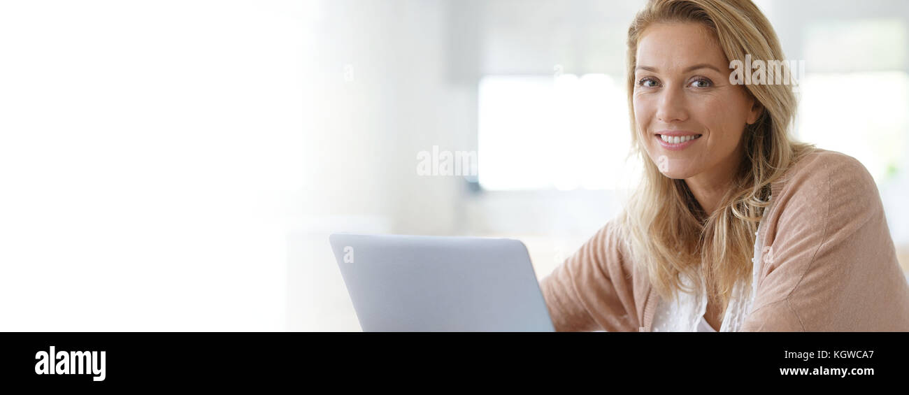 Attractive blonde woman working on laptop computer at home Banque D'Images