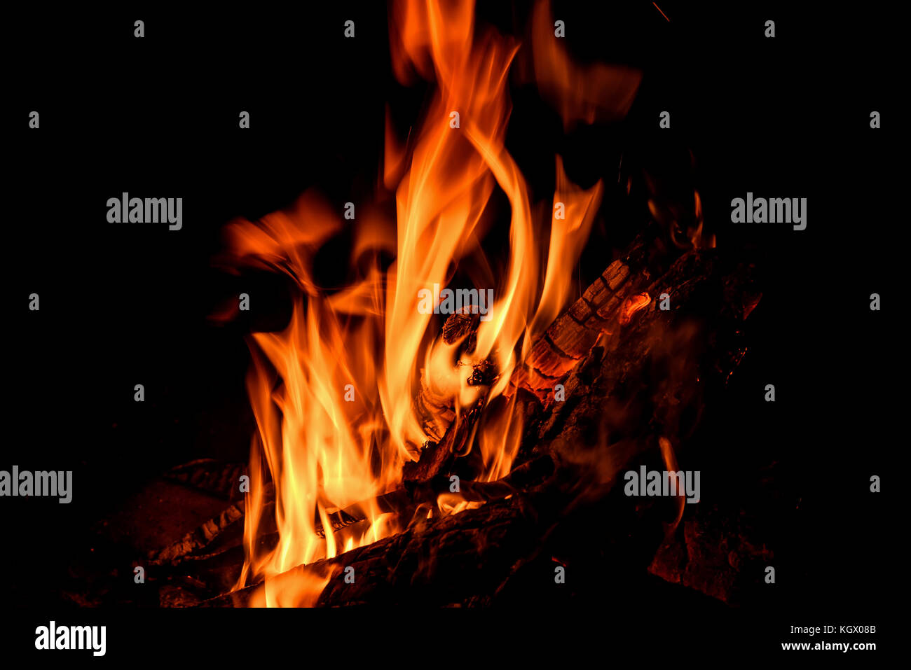 Orange et rouge des jaillissements de flammes, de charbon et de bois dans le feu sur un fond noir Banque D'Images