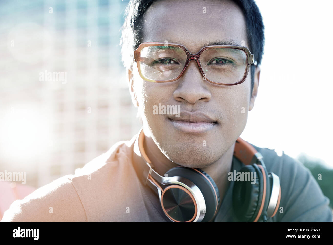 Portrait of smiling mixed couru guy avec de la musique à l'extérieur du casque dans park Banque D'Images