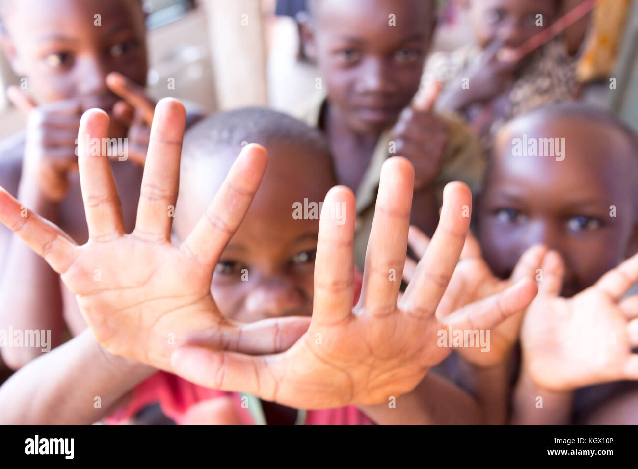 Une bande d'enfants ougandais au hasard dans la rue en riant, souriant, agitant et avoir du plaisir devant la caméra. Banque D'Images