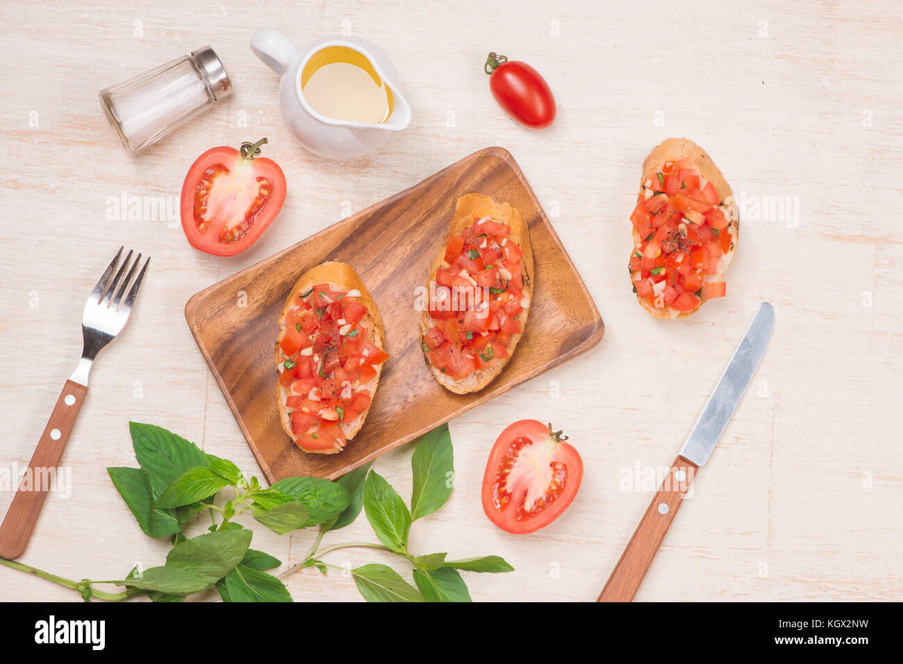 La préparation de délicieux plats italiens Bruschetta aux tomates avec des morceaux de légumes, herbes et l'huile Banque D'Images